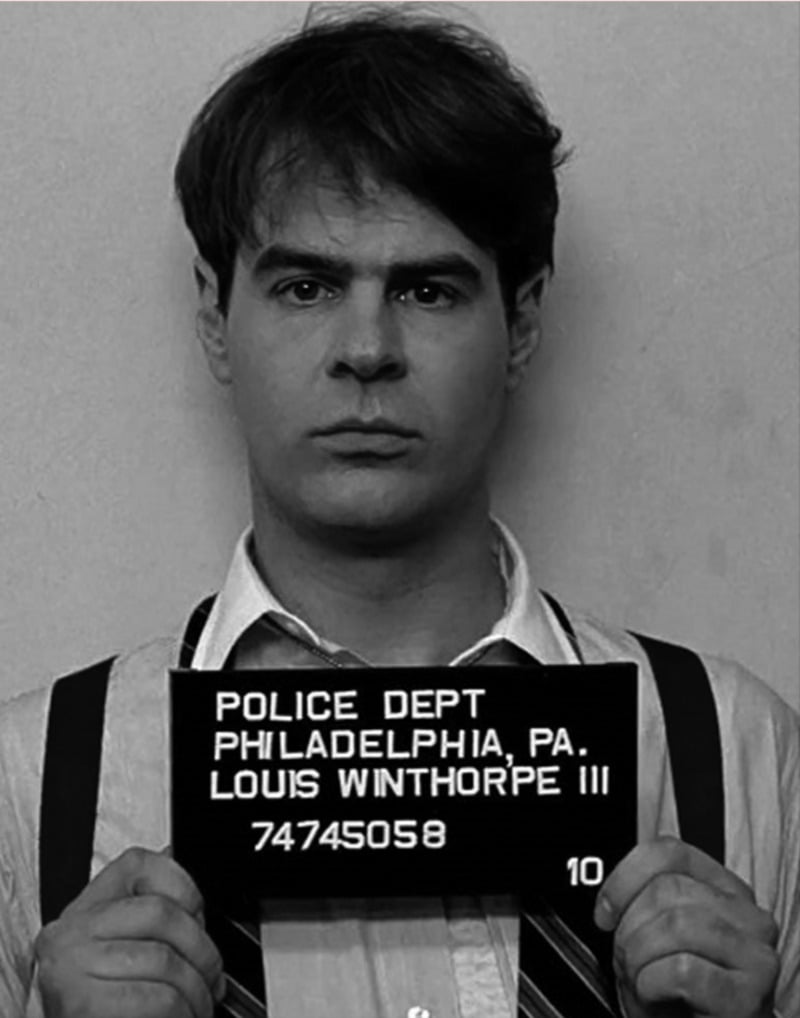 Black and white mugshot of a man with short hair, wearing a collared shirt and suspenders, holding a sign that reads: "Police Dept Philadelphia, PA. Louis Winthorpe III 74745058.