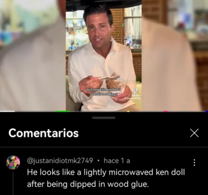 A man in a white shirt sits indoors, holding a bowl and spoon. Below, a comment reads: "He looks like a lightly microwaved Ken doll after being dipped in wood glue.