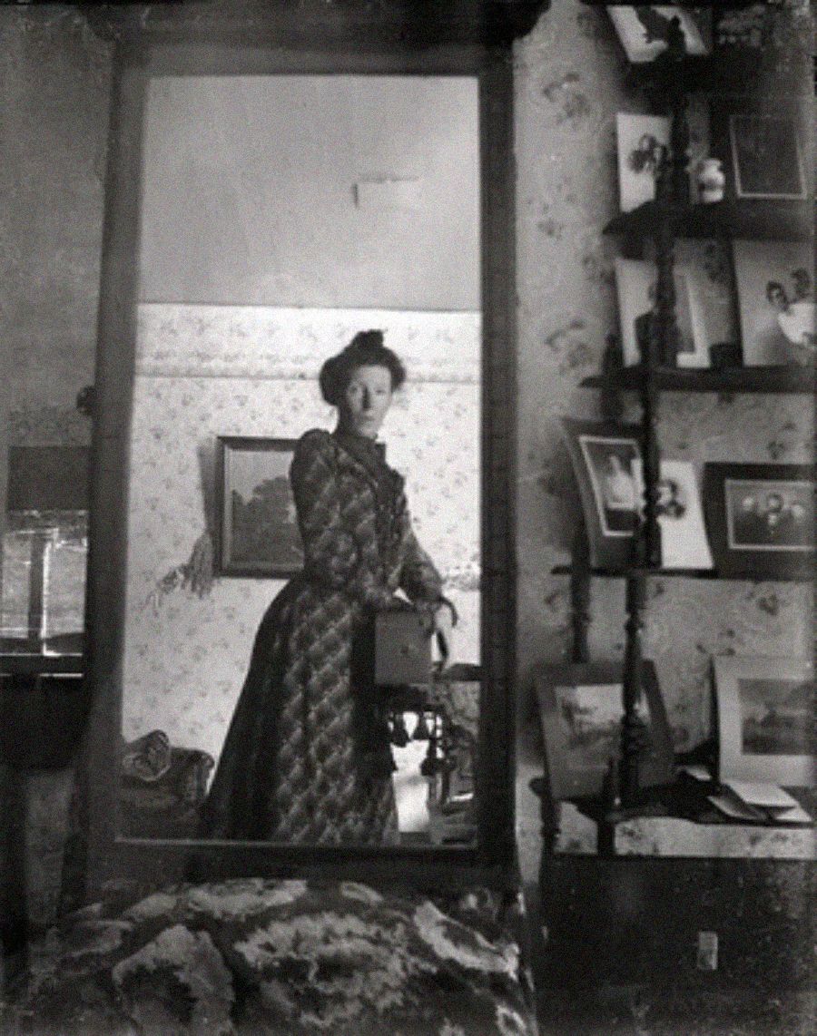 A woman in a dress standing in a room with a mirror