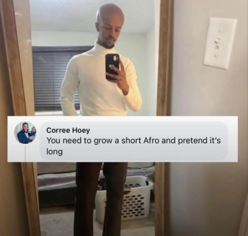 A man with a shaved head wearing a white turtleneck and dark pants takes a mirror selfie. Overlaid is a comment: "You need to grow a short Afro and pretend it's long." A laundry basket is visible in the background.