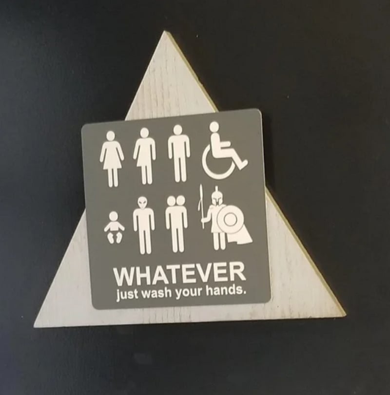 A bathroom sign shows various gender symbols, a baby, a person in a wheelchair, and a figure with a cape and spear. Text reads: "WHATEVER just wash your hands.