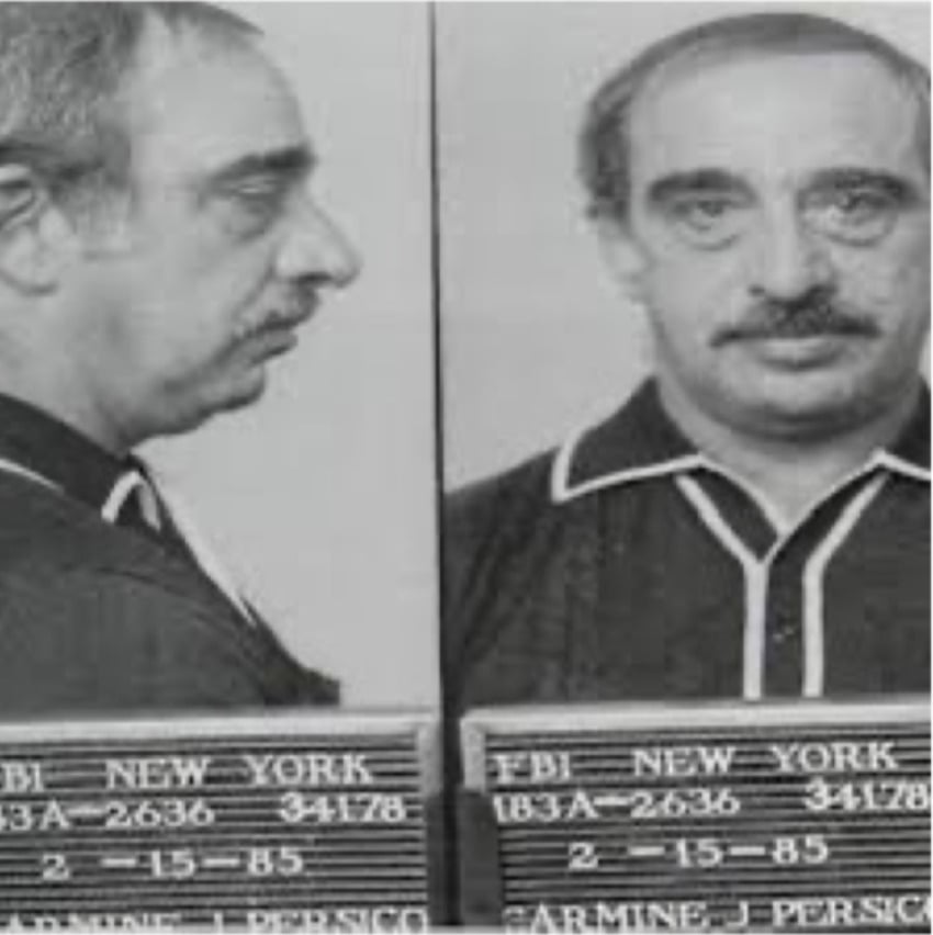 Black-and-white mugshot of a middle-aged man with short hair and a mustache, shown in both profile and front views, holding a placard with identification details.