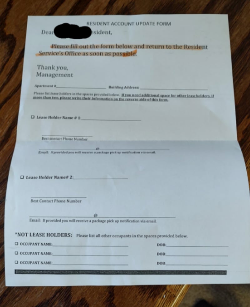 A printed resident account update form on a wooden surface, requesting residents to fill in lease holder and occupant details, including names, contact numbers, and dates of birth. Some text is highlighted in orange.