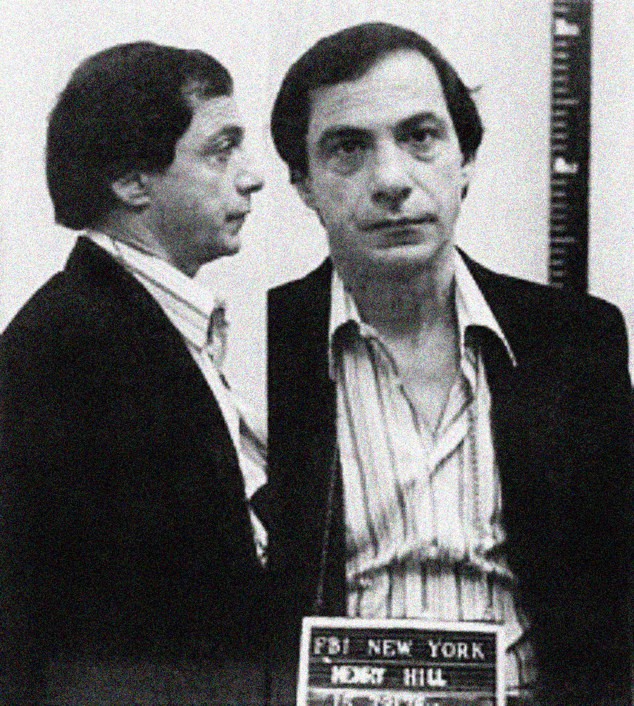 Black and white mugshot of a man with dark hair, wearing a striped shirt and dark jacket, shown in both side and front profile. He is holding a sign that reads "FBI NEW YORK" with other text below.