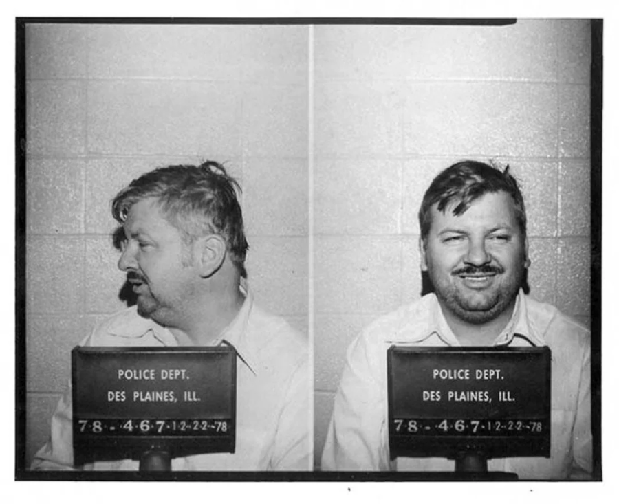 Mugshot with two views of a man wearing a white shirt, taken at the Des Plaines, Illinois Police Department. He is looking left in one photo and facing forward, smiling, in the other.