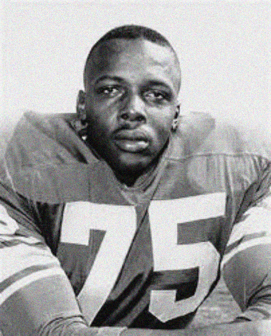 Black and white photo of a football player wearing a jersey with the number 75. He looks serious, with short hair, and is posed facing the camera.
