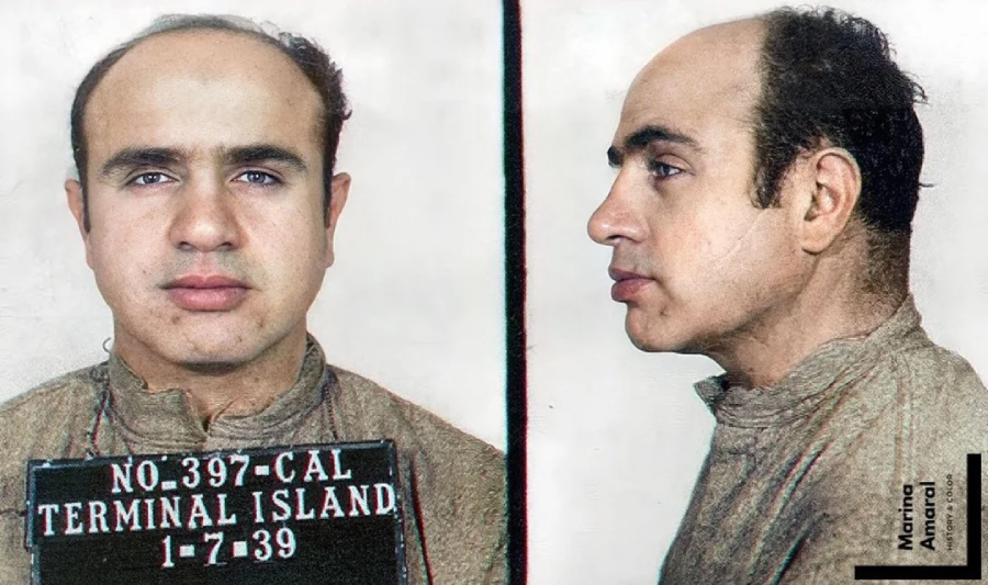 Colorized mugshot photo showing a man with thinning hair, wearing a high-collared shirt, facing front and side. He holds a sign reading "NO. 397 - CAL TERMINAL ISLAND 1-7-39.