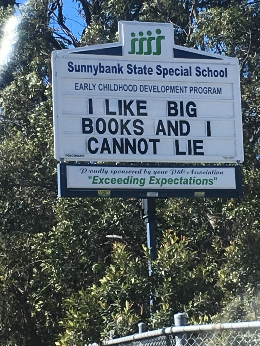 A school sign at Sunnybank State Special School reads: "I LIKE BIG BOOKS AND I CANNOT LIE." Trees and greenery are visible in the background.