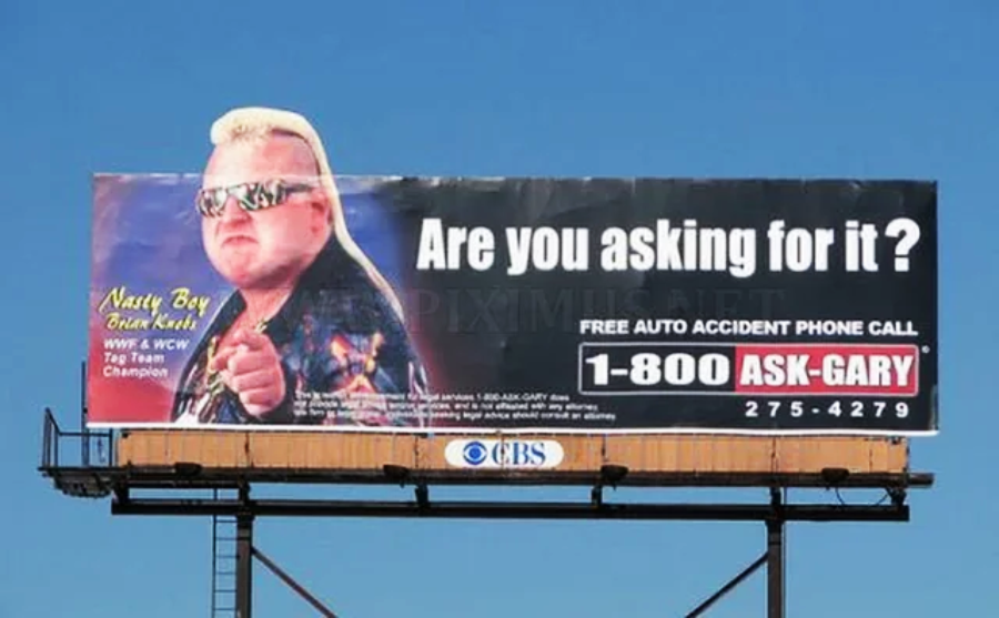 A billboard shows wrestler Brian Knobbs pointing, with text reading "Are you asking for it?" and an ad for free auto accident phone calls with the number 1-800-ASK-GARY.