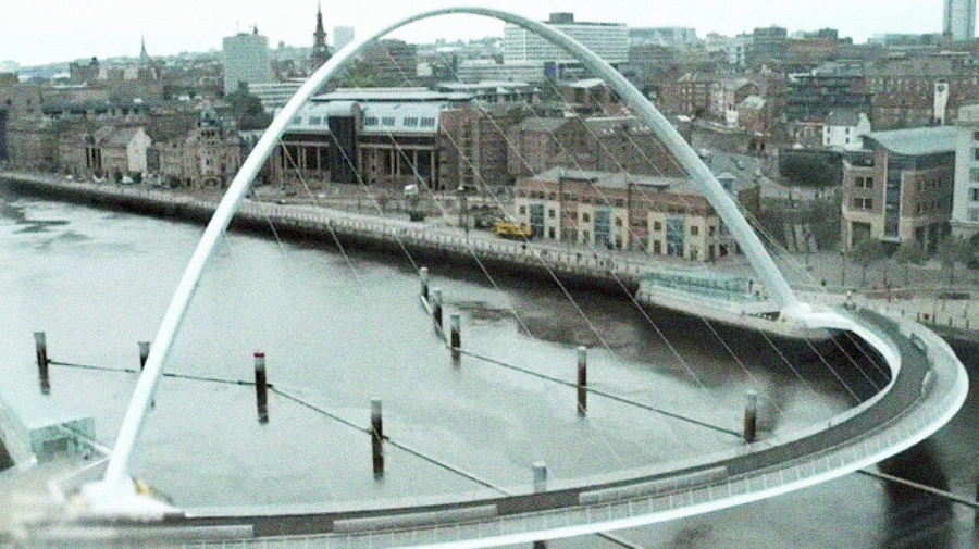 A modern, tilting pedestrian and cyclist bridge with a curved arch spans over a river, connecting two sides of a city with historic and contemporary buildings visible in the background.