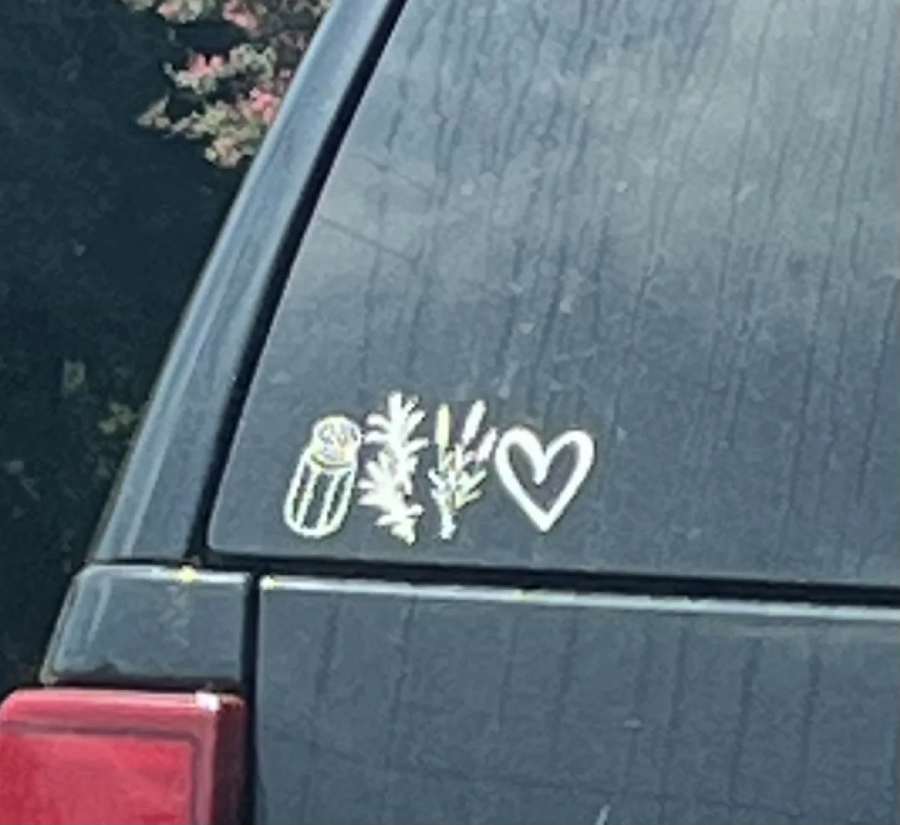 A car sticker on a rear window shows images of a pickle, dill, and a heart shape, suggesting the phrase "I love pickles and dill.