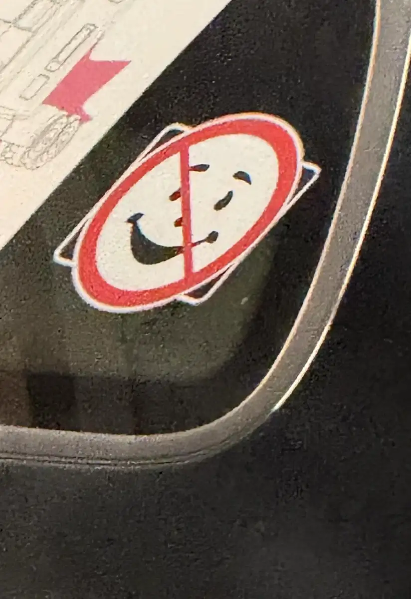 A sticker on a window shows a smiling face inside a red circle with a diagonal slash, resembling the Ghostbusters logo but with a happy face instead of a ghost.
