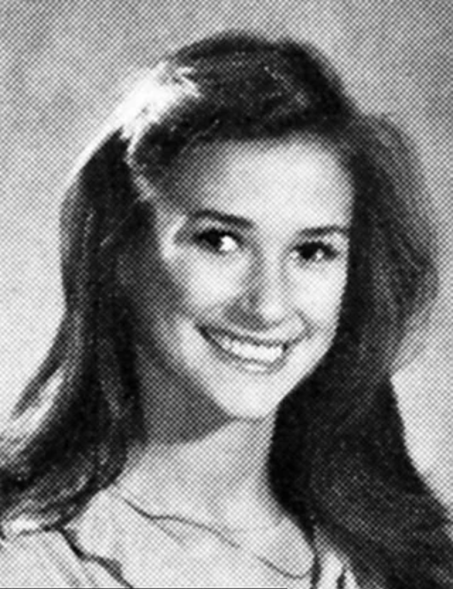 Black and white yearbook-style portrait of a young woman with long dark hair, smiling, and wearing a light-colored top, posed in front of a plain background.