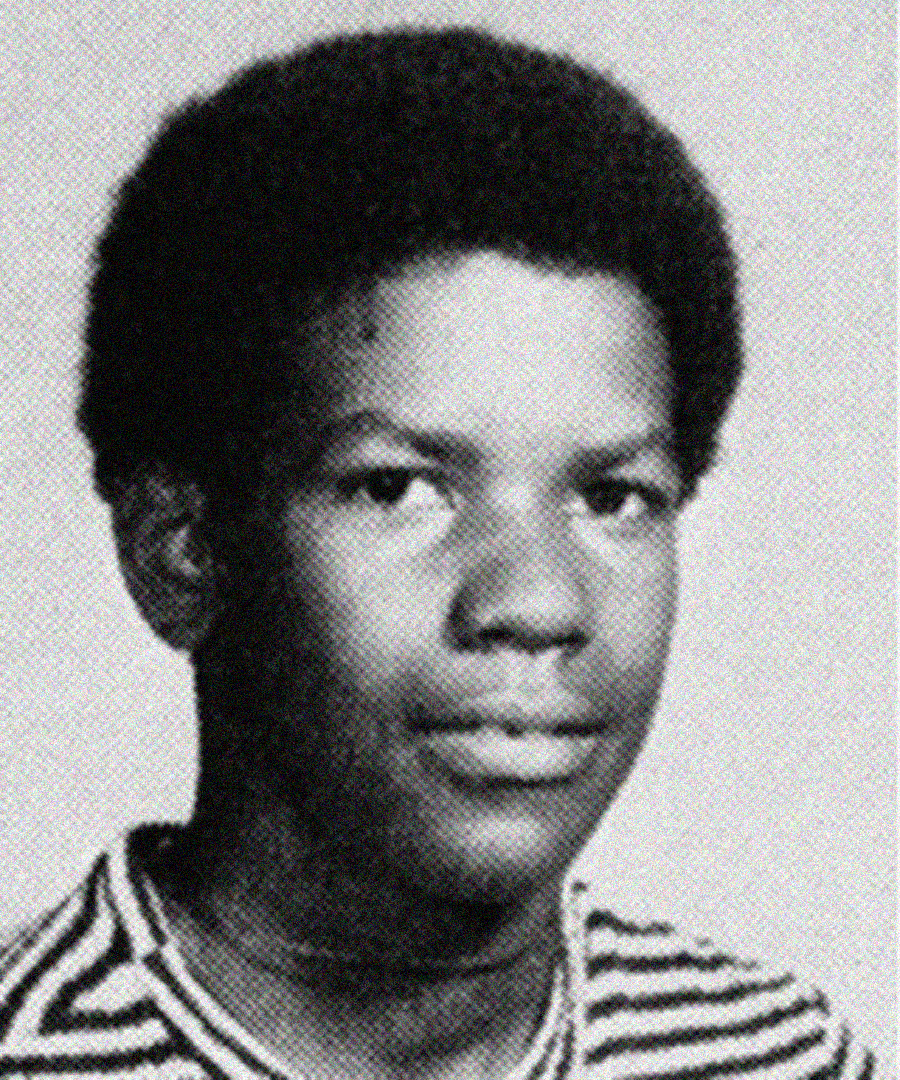 Black and white yearbook-style portrait of a young boy with short curly hair, wearing a striped shirt, looking at the camera with a neutral expression.