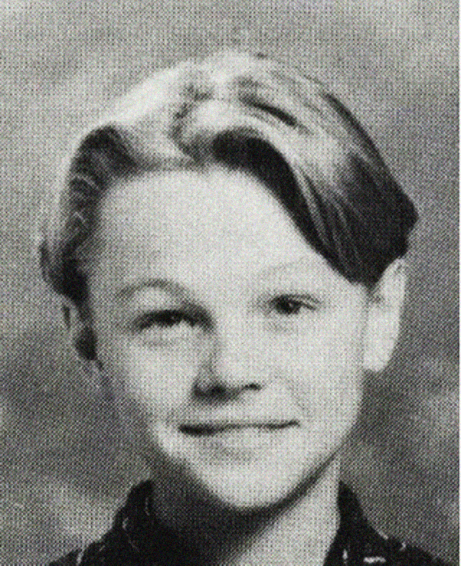 Black and white portrait of a young boy with light-colored hair parted to the side, smiling slightly, and wearing a patterned shirt. The background is plain and out of focus.