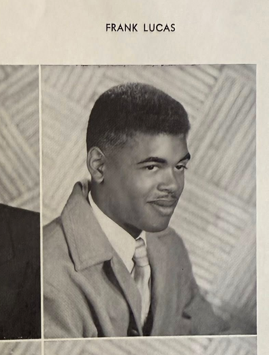 A young man in a suit and tie poses for a formal black-and-white portrait. The name “Frank Lucas” is printed above the photo, and the background features a geometric, patterned design.