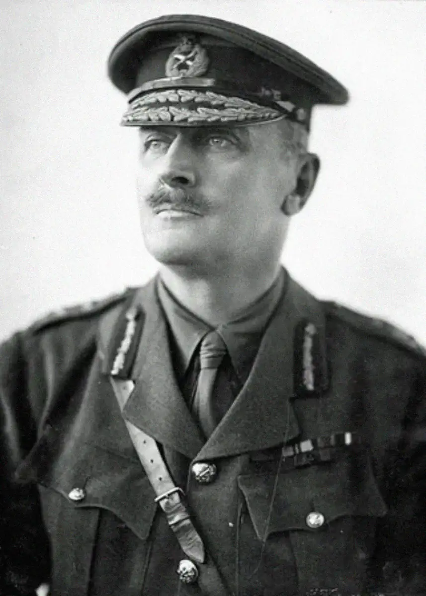 A black and white portrait of a man in a decorated military uniform and cap, looking slightly upward and to the side, with a mustache and visible medals on his chest.