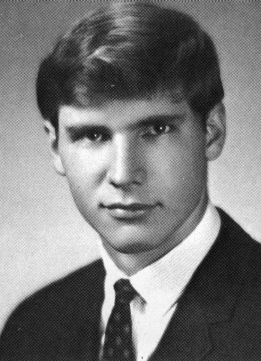 Black and white portrait of a young man wearing a suit, white shirt, and patterned tie. He has short, neatly combed hair and a serious expression, looking directly at the camera against a plain background.