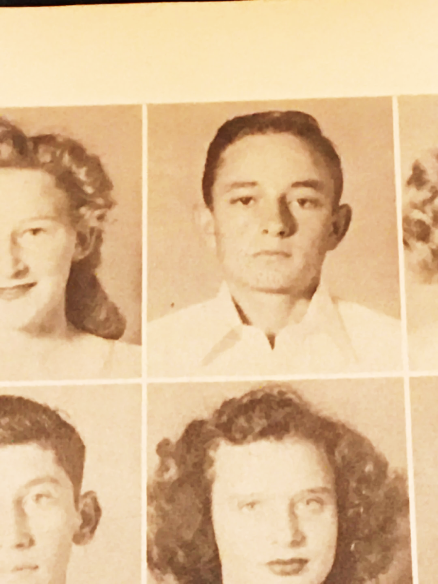 A sepia-toned yearbook page shows four portraits. The center photo is of a young man in a white collared shirt with short dark hair, looking straight ahead with a neutral expression.