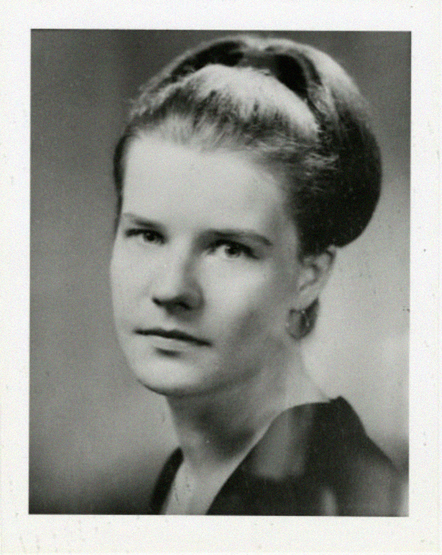Black and white portrait of a woman with light skin and her hair pulled back in a neat updo, wearing earrings and a dark top, looking slightly to the left of the camera with a neutral expression.
