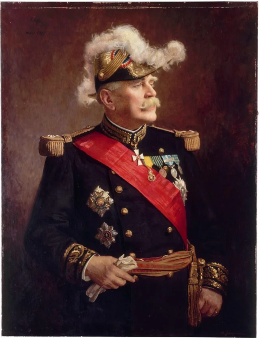 Portrait of an older man in a decorated military uniform with medals, a red sash, and a feathered hat, standing with one hand resting on his sword, looking to the side against a dark background.
