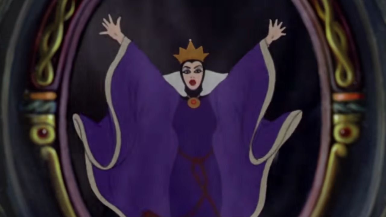 Animated queen in a purple robe and gold crown stands with raised arms inside an ornate oval mirror, with a dramatic expression on her face.