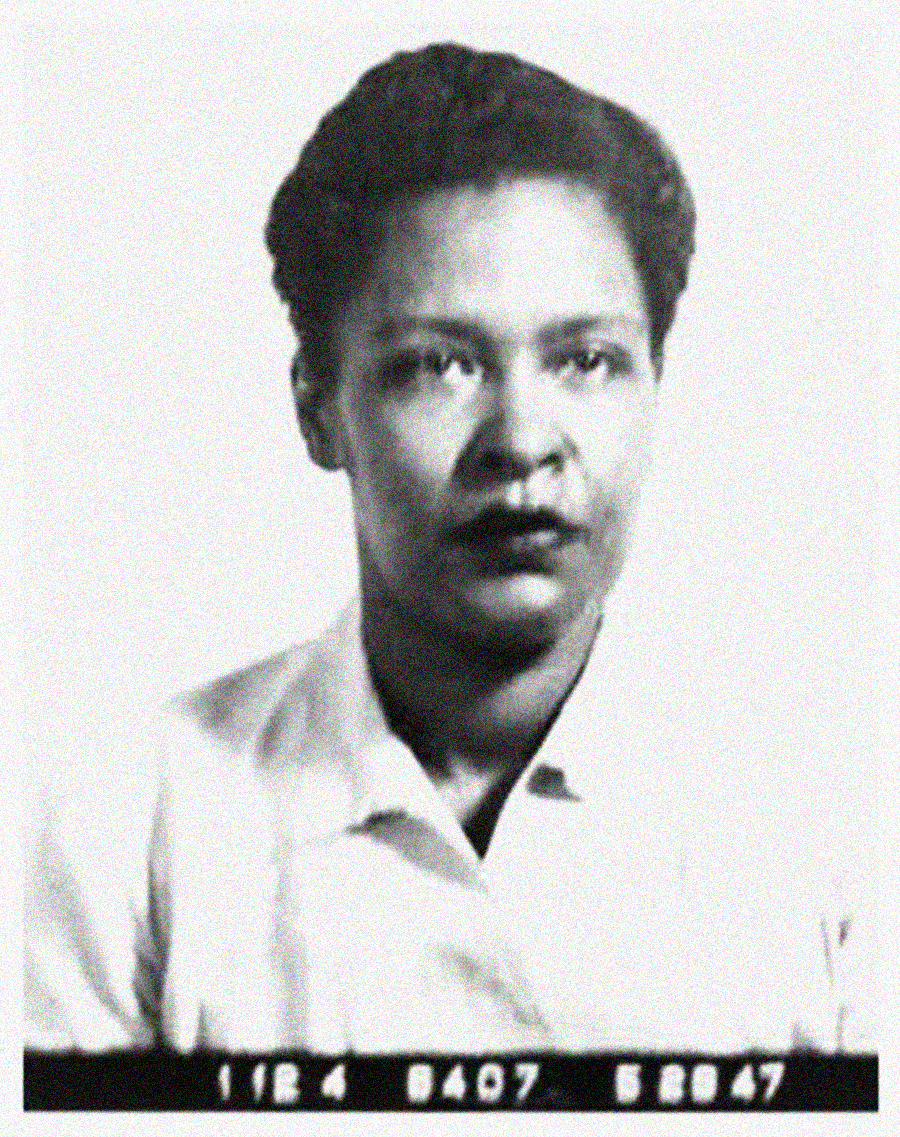 Black-and-white photograph of a woman with short hair wearing a light-colored collared shirt, facing forward with a neutral expression, against a plain background. Numbers are visible along the bottom edge.