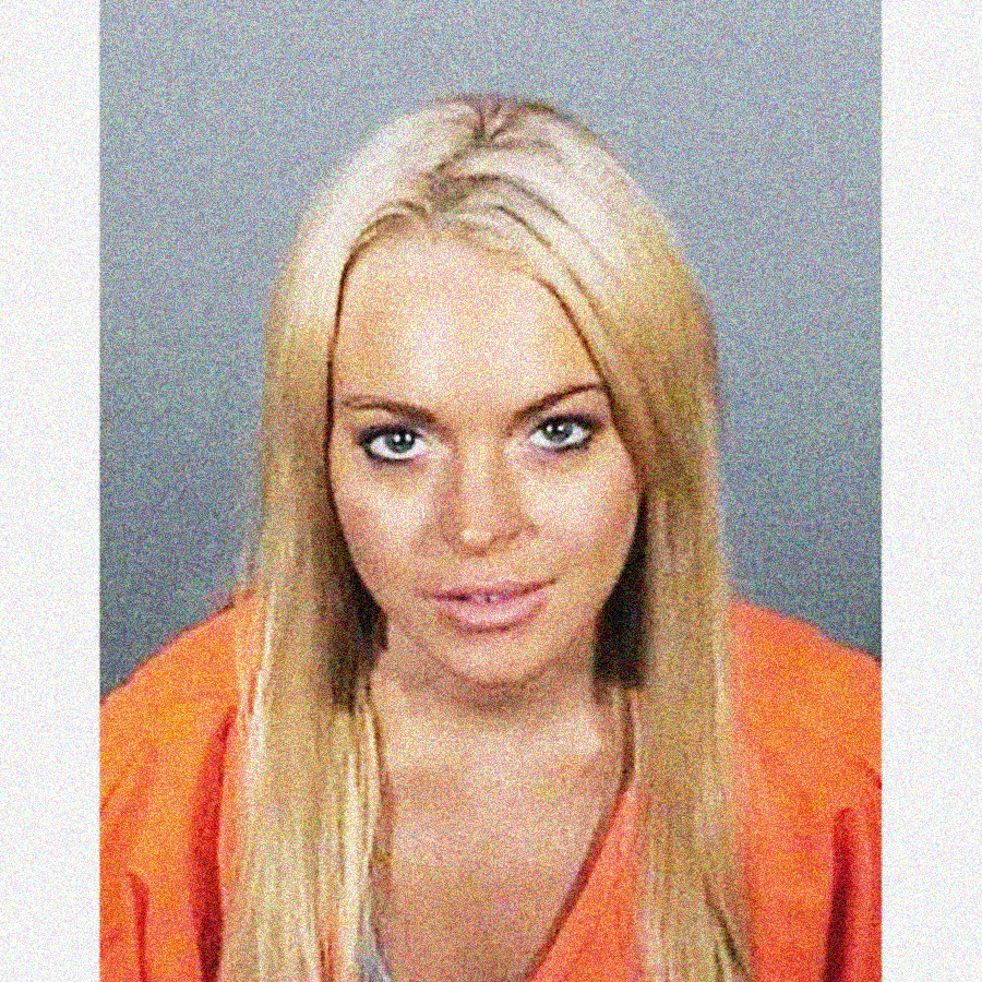 A woman with long blonde hair wearing an orange top looks directly at the camera against a gray backdrop, similar to a mugshot.