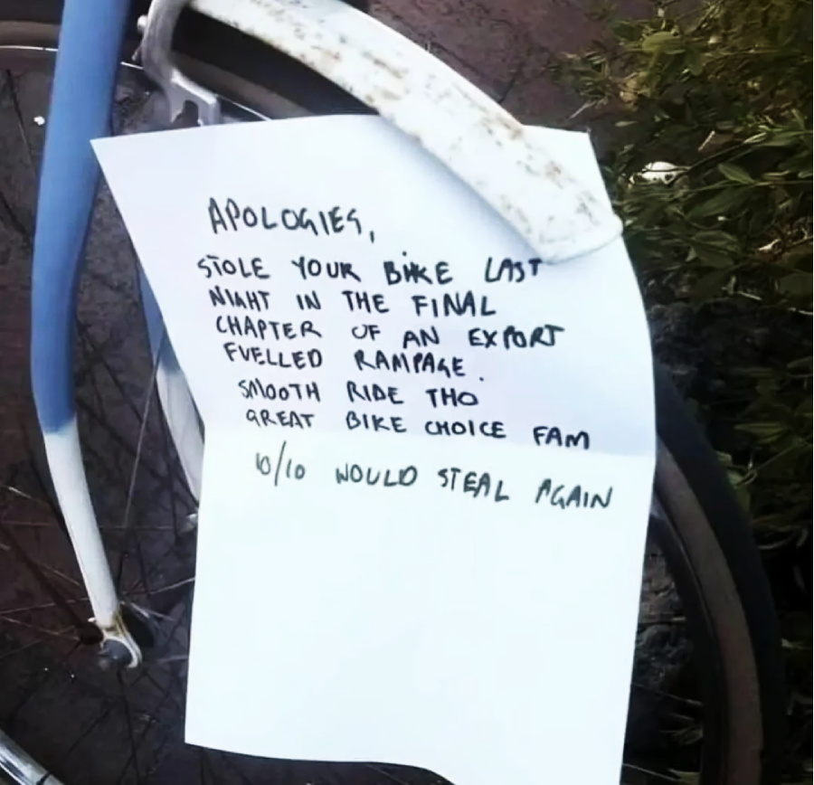 A handwritten note is attached to a bicycle. The note apologizes for stealing the bike, compliments the bike's quality, and humorously rates it "10/10 would steal again.