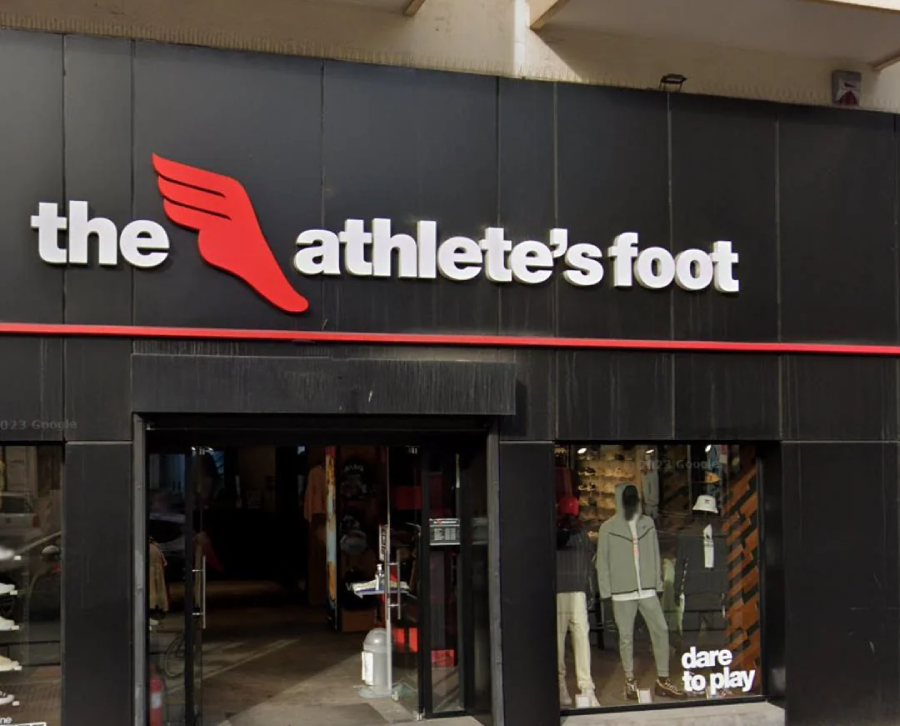 Storefront of "The Athlete's Foot" with bold white and red logo above the entrance, featuring a red wing. Mannequins in athletic wear are visible through the glass windows.
