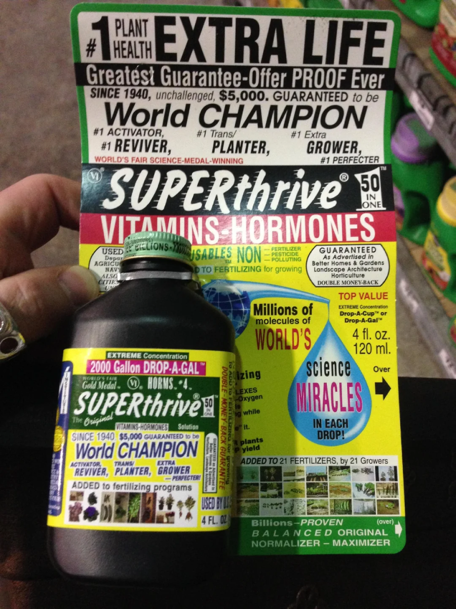 A person holds a bottle of SUPERthrive plant supplement in front of its colorful packaging, which displays bold claims about plant health benefits, awards, and usage instructions with lots of text and graphics.
