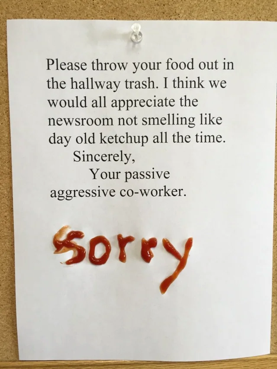 A typed note asks coworkers to throw food in the hallway trash to avoid a newsroom smelling like old ketchup. At the bottom, "sorry" is written in ketchup, adding a passive-aggressive touch.