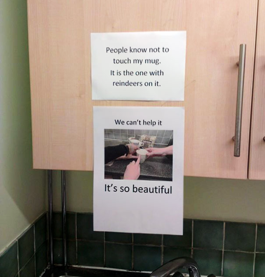 Two printed signs on a kitchen cabinet. The top sign says, "People know not to touch my mug. It is the one with reindeers on it." The lower sign shows hands reaching for a mug and says, "We can't help it. It's so beautiful.