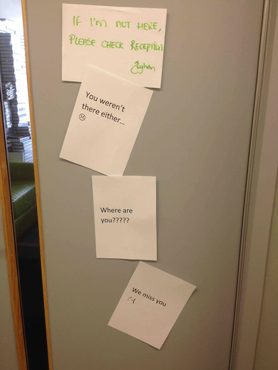 Four notes are taped to a door. The top note reads, "If I'm not here, please check reception." The three notes below respond: "You weren't there either...," "Where are you?????," and "We miss you :'(.