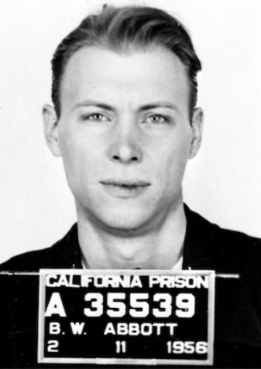 Black and white mugshot of a man with light hair. He is facing forward, holding a sign that reads "California Prison A 35539 B.W. Abbott 2 11 1956.