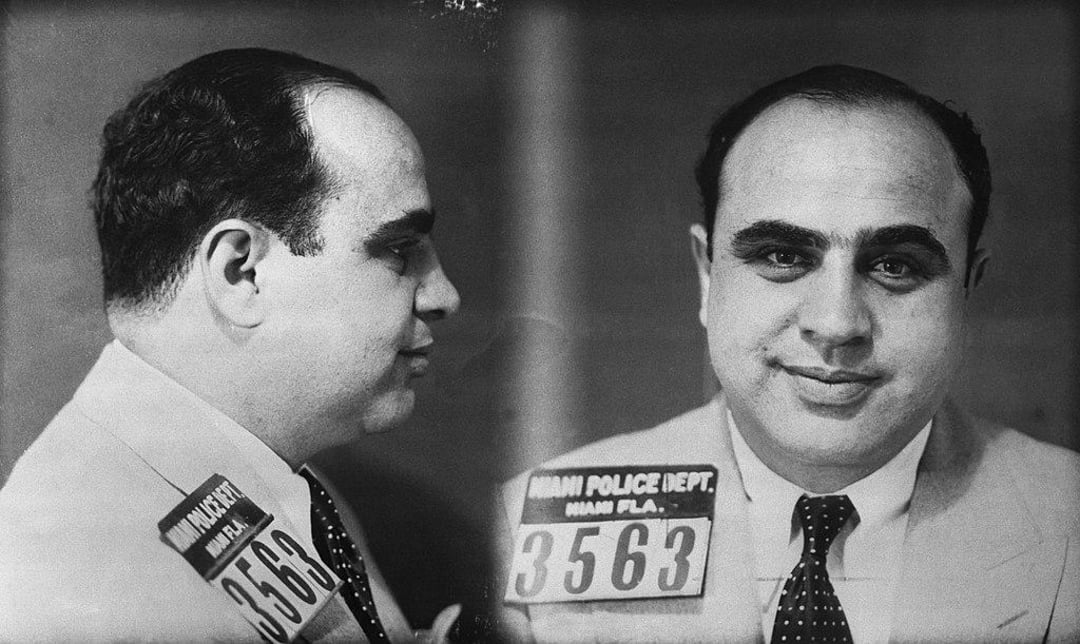 A black-and-white mugshot photo showing a man in a suit and tie, facing forward and in profile. He is holding a sign with the number 3563 and "Miami Police Dept., Miami, Fla.