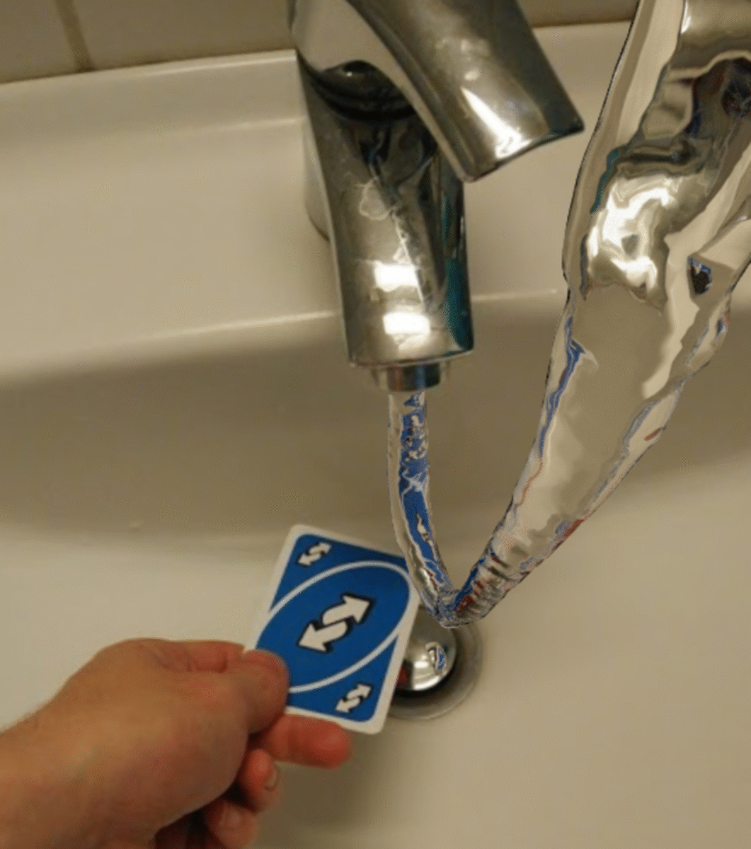 A hand holds a blue Uno reverse card under a running faucet, and the water appears to flow back up into the tap instead of down the drain.