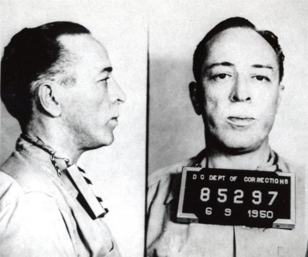 Black and white mugshot of a man in two views, profile and front-facing. He holds a sign reading "D.C. Dept of Corrections 85297 6 9 1950.