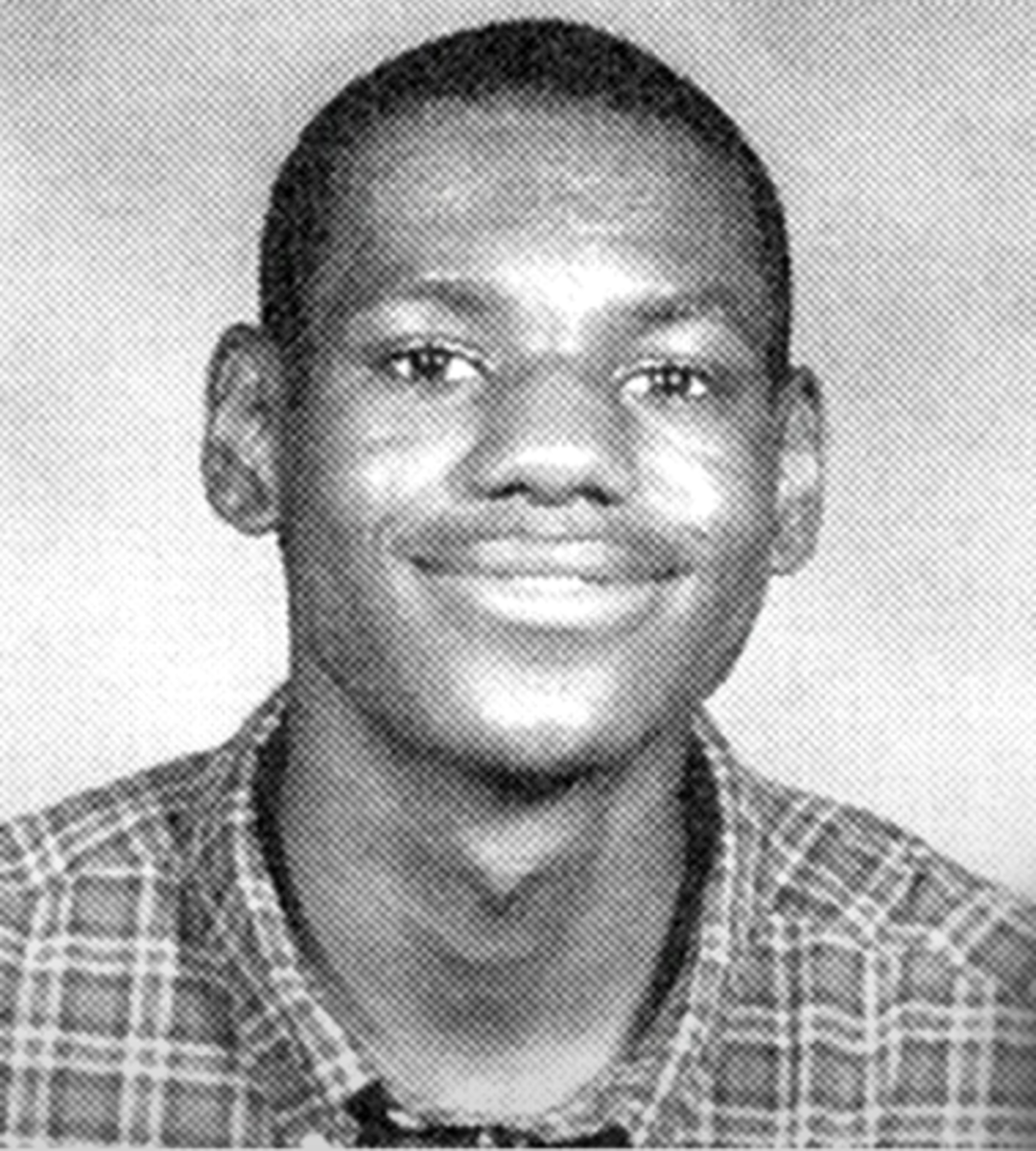 Black and white yearbook-style portrait of a young person smiling, wearing a plaid shirt, with short hair, facing the camera against a plain background.