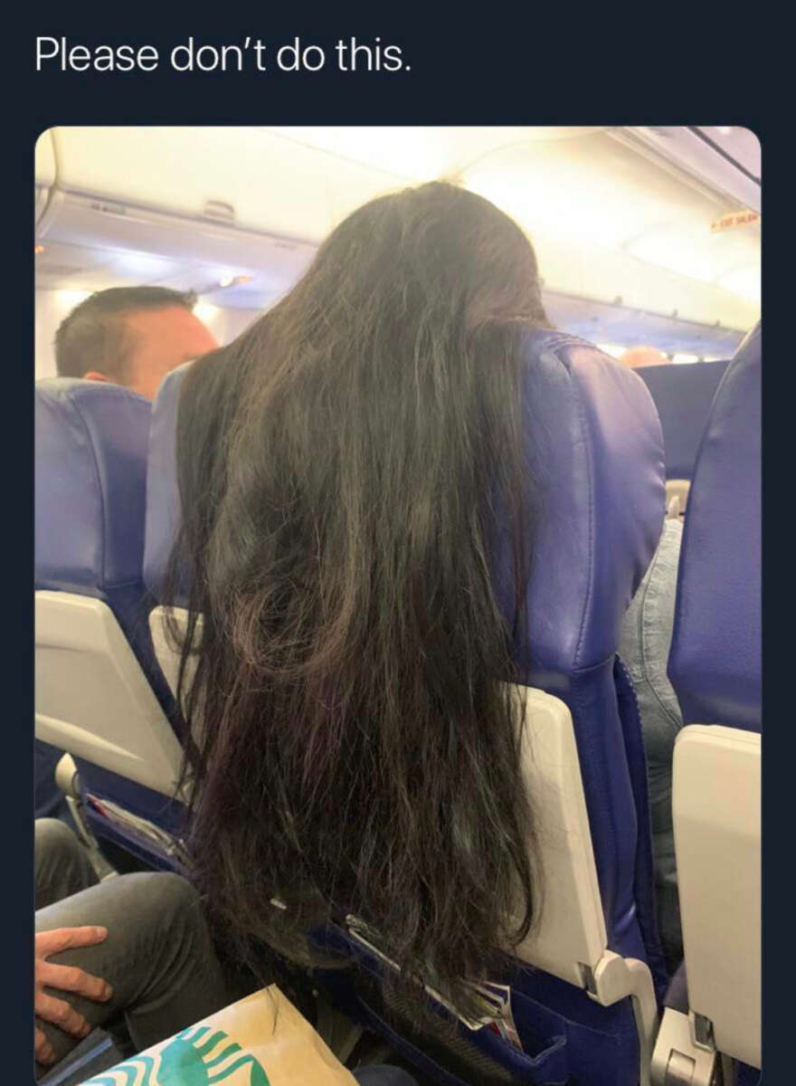 A person with very long hair drapes it over the back of an airplane seat, covering the tray table of the passenger behind them. Text at the top reads, "Please don’t do this.