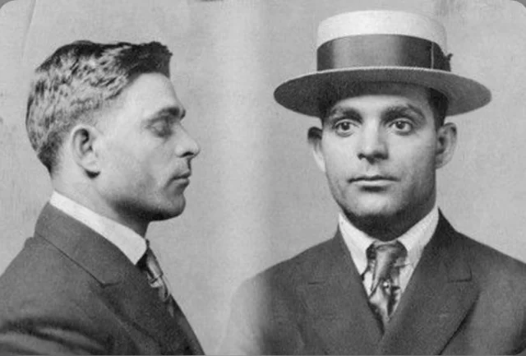 Black and white mugshot of a man in a suit and tie. On the left, he faces sideways; on the right, he faces forward wearing a boater hat. Both photos show a neutral expression.