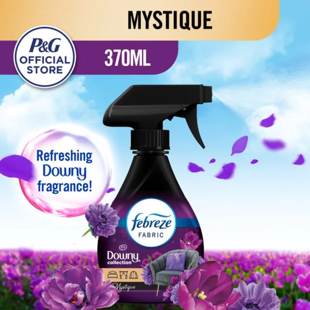 A 370ml spray bottle of Febreze Fabric Downy Mystique is shown with purple flowers and a purple couch. The label highlights "Refreshing Downy fragrance" and "P&G Official Store" against a blue sky background.