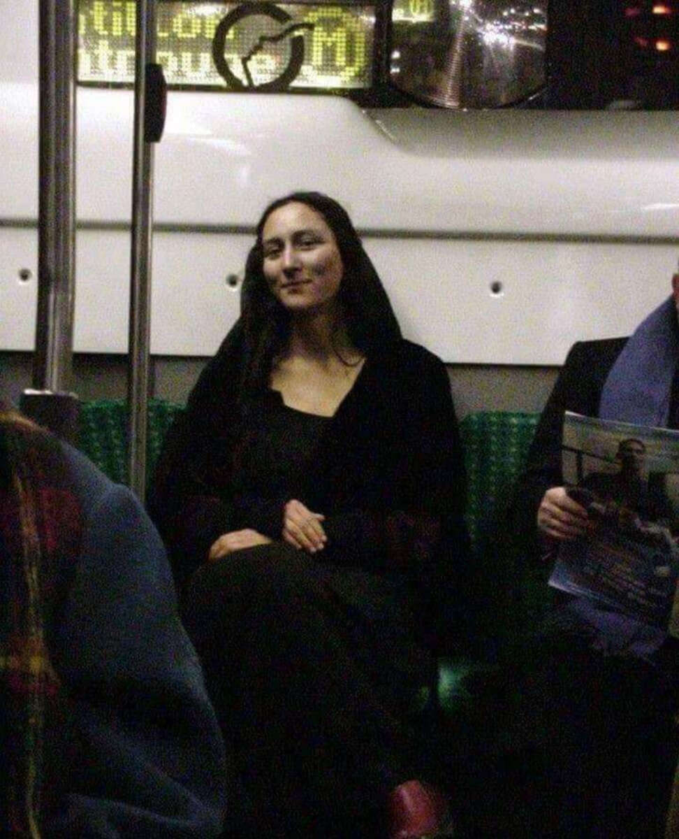 A woman with long dark hair and a serene expression, dressed in dark clothing, sits on a subway seat, resembling the Mona Lisa. Other passengers are nearby, and a digital display is visible above her.