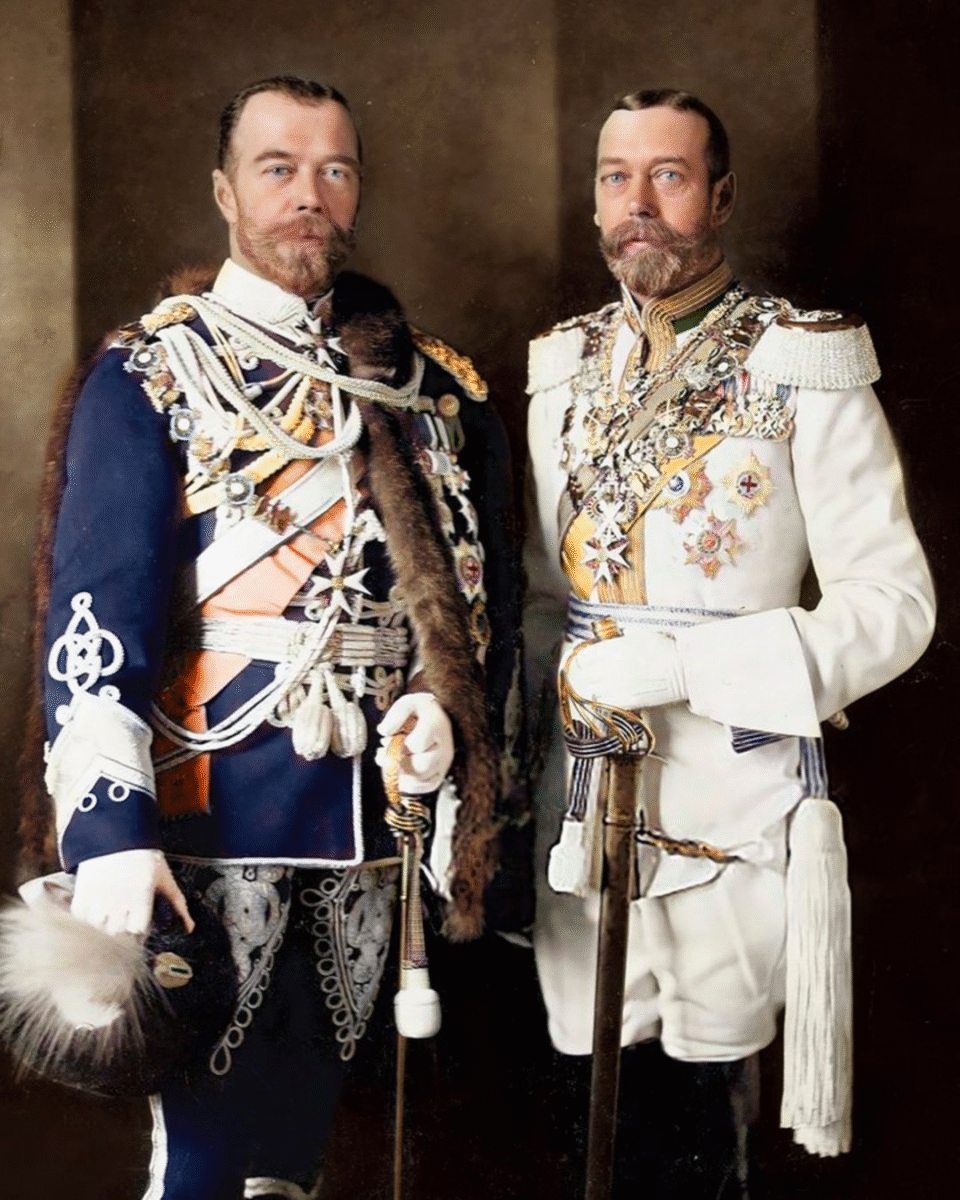 Two men in ornate military uniforms, decorated with medals and sashes, stand side by side. One wears a dark uniform with fur trim, the other wears white. Both have neatly groomed beards and serious expressions.
