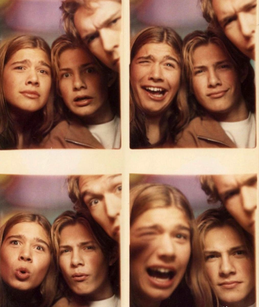 Four-photo strip of three young people with long hair making silly faces and expressions close together, as if in a photo booth, against a blurred background.