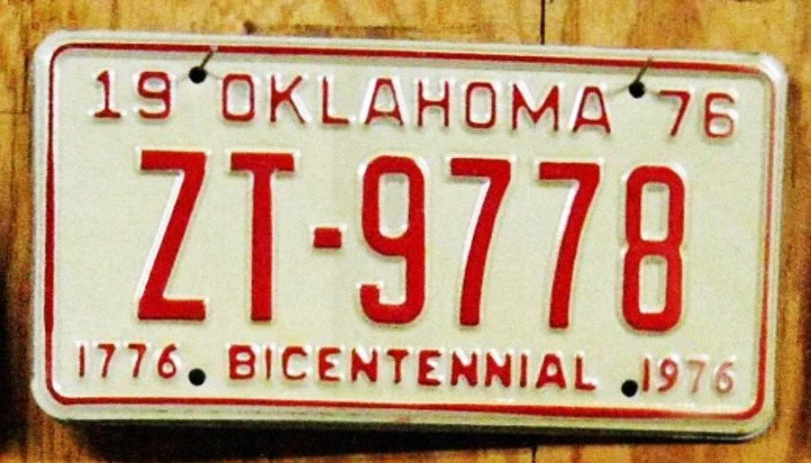 A vintage Oklahoma license plate from 1976 with red letters and numbers "ZT-9778" and the words "1776 BICENTENNIAL 1976" at the bottom, mounted on a wooden surface.