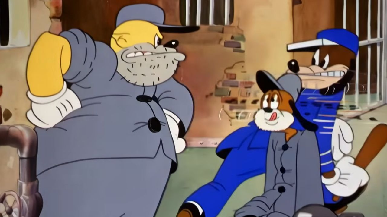 Three animated dogs in gray and blue prison uniforms are gathered in front of a weathered brick wall with barred windows, appearing to be in a tense conversation.