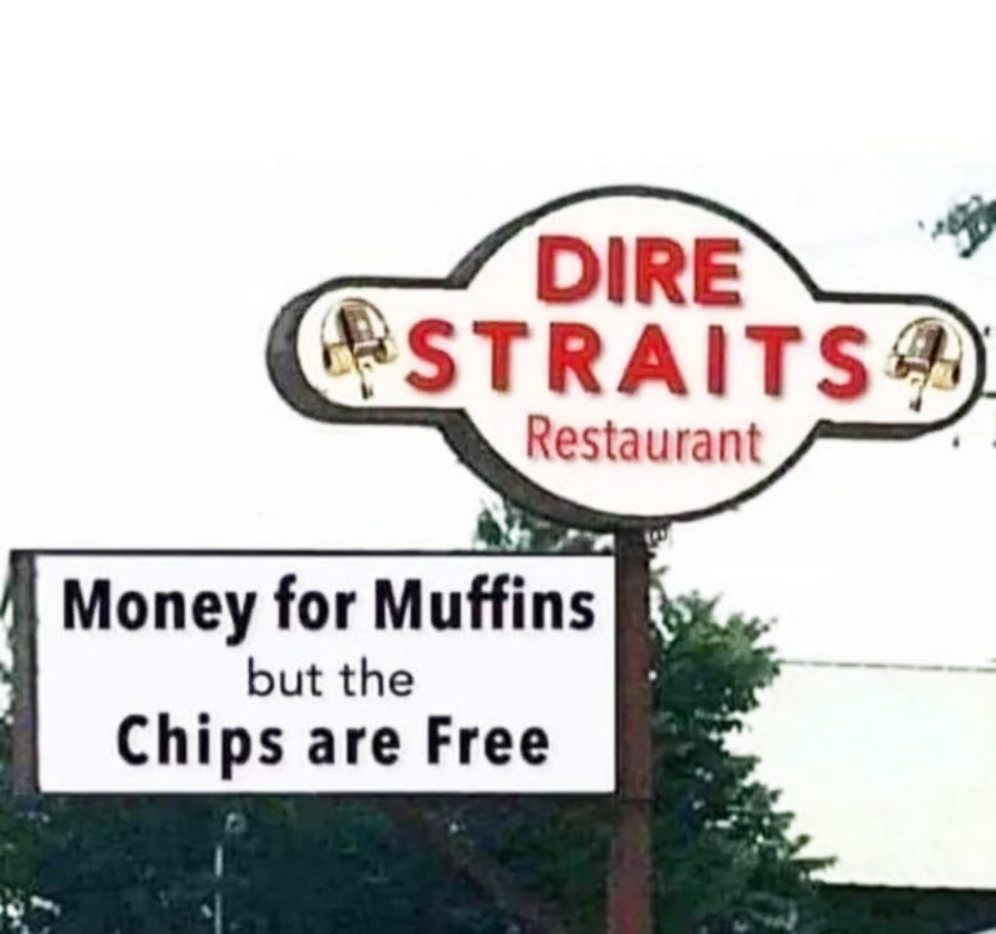 A restaurant sign reads “DIRE STRAITS Restaurant.” Below it, another sign says, “Money for Muffins but the Chips are Free.” The signs reference the band Dire Straits and their famous song “Money for Nothing.”