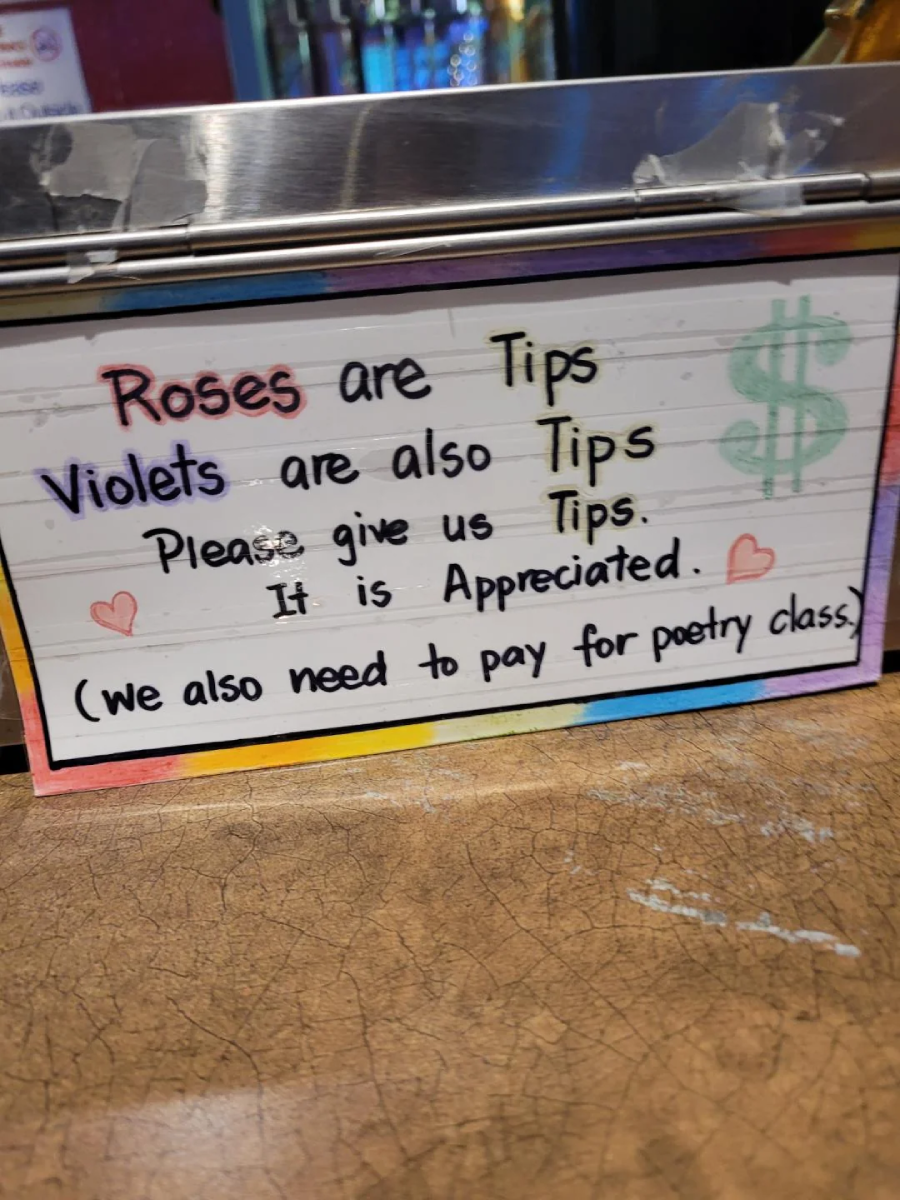A colorful sign reads: “Roses are Tips, Violets are also Tips. Please give us Tips. It is Appreciated. (we also need to pay for poetry class)” with hand-drawn hearts and a dollar sign.