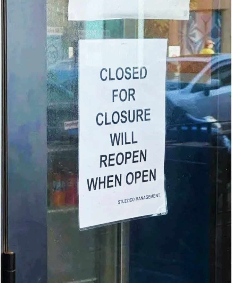 A printed sign on a glass door reads, "CLOSED FOR CLOSURE WILL REOPEN WHEN OPEN" with "STUZZICO MANAGEMENT" at the bottom. A street and parked car are visible through the glass.